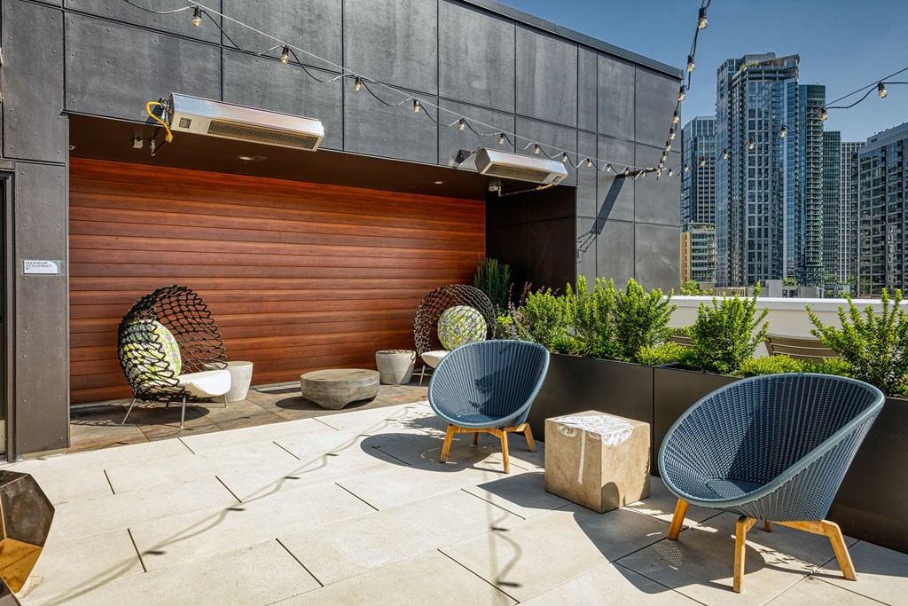 a rooftop patio with two chairs and a wooden wall with a city in the background