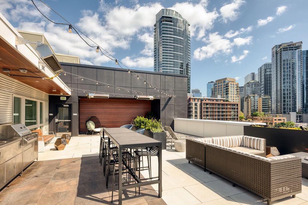 a rooftop patio with a table and chairs and a city in the background
