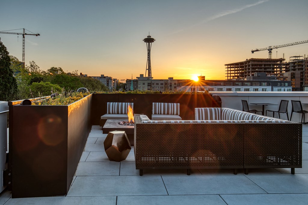 a rooftop terrace with a view of the city and a sunset