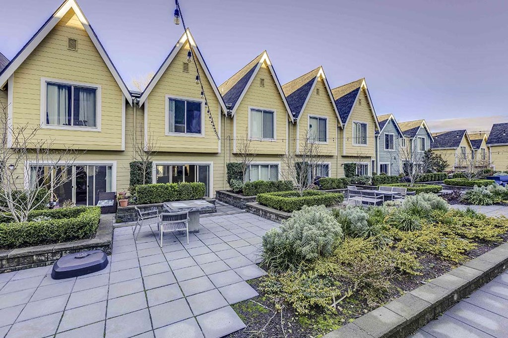 a row of yellow houses with a courtyard with a table and chairs