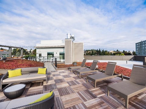 A patio with a white couch and chairs with a building in the background.