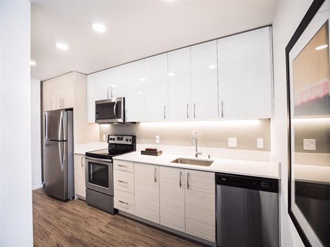 A modern kitchen with white cabinets and stainless steel appliances.