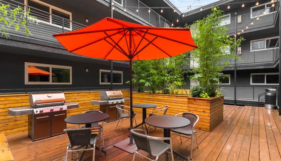 a patio with an orange umbrella and tables with chairs