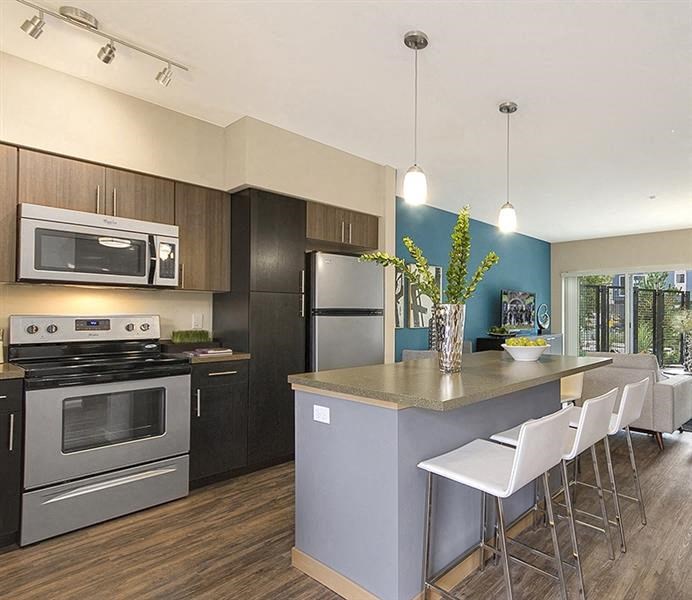 a kitchen with stainless steel appliances and a bar with white chairs