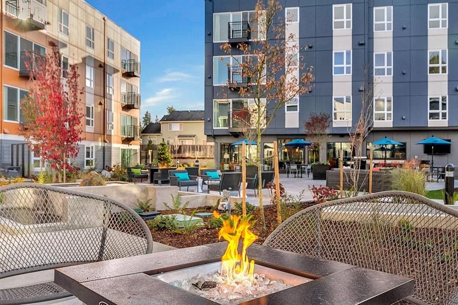 an outdoor patio with a fire pit in front of an apartment building