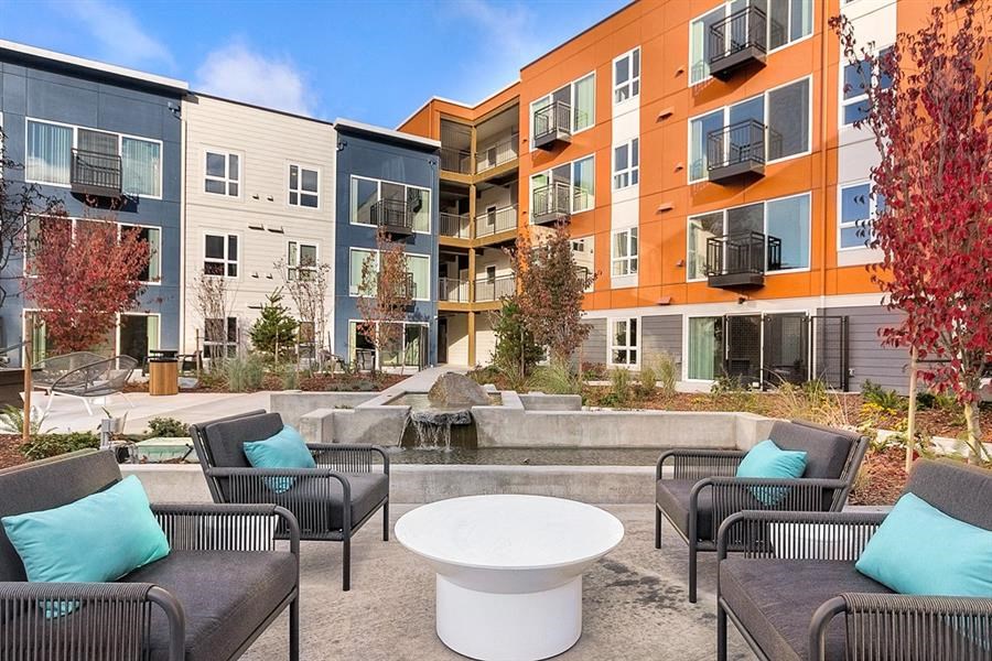 an outdoor patio with chairs and tables in front of an apartment building