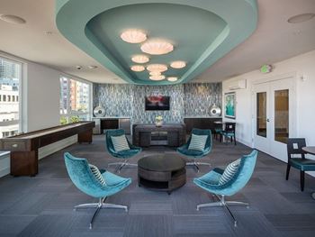 a lounge area with blue chairs and a brown table with a television on the wall