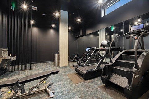 A gym with treadmills, a bench, and a table.