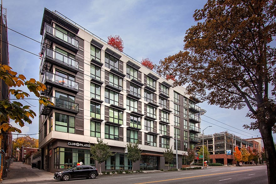 a large white building with green windows and a black car parked in front of it