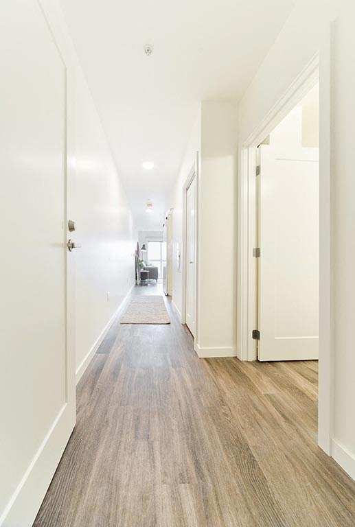 a hallway with white walls and wood floors