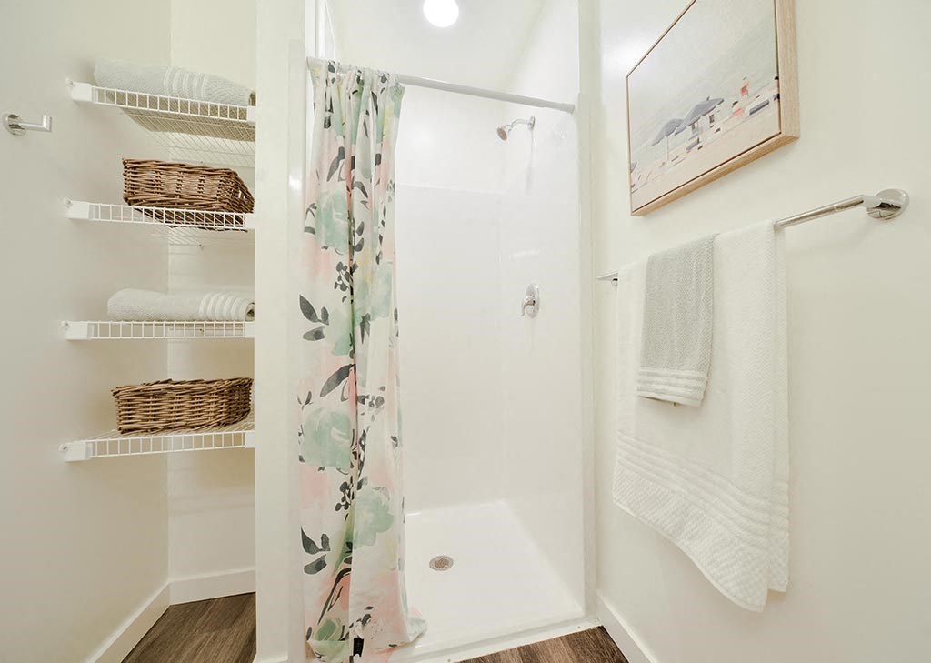 a walk in shower with a floral shower curtain and white towels