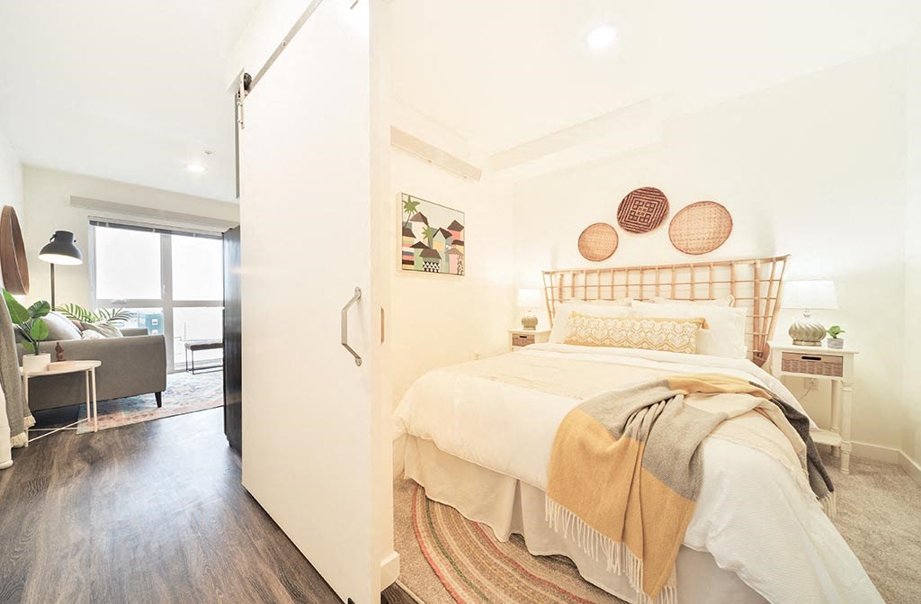 a bedroom with a bed and a door to a living room