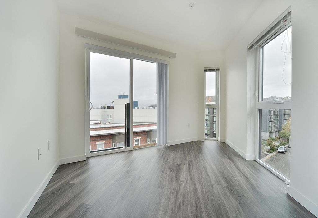 a bedroom with a large window and hardwood floors