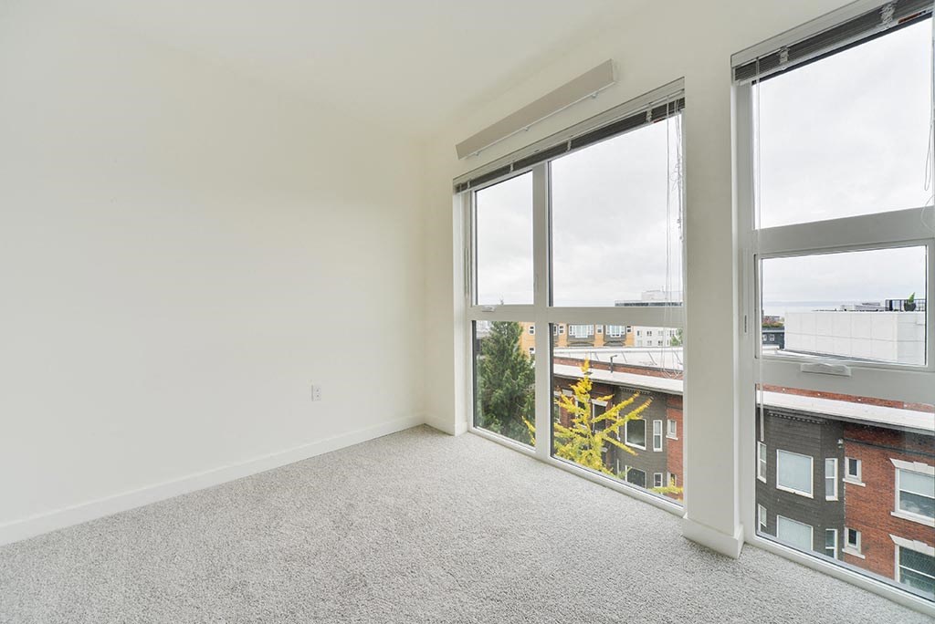 a bedroom with a large window and a view of a building