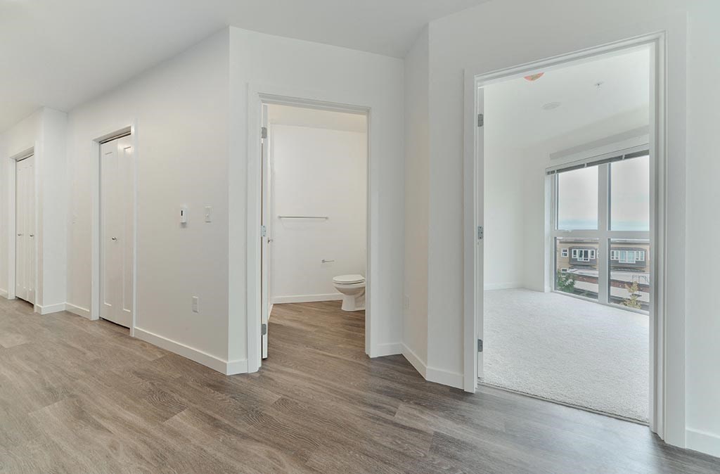 a bedroom with white walls and wood flooring