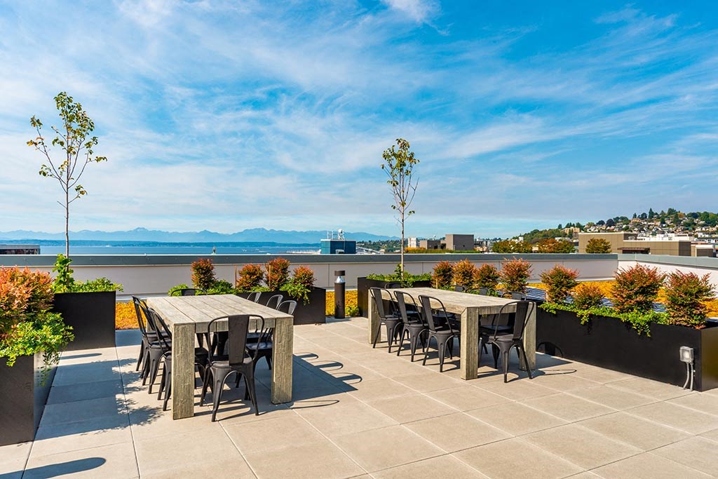 a rooftop patio with tables and chairs and a view of the water