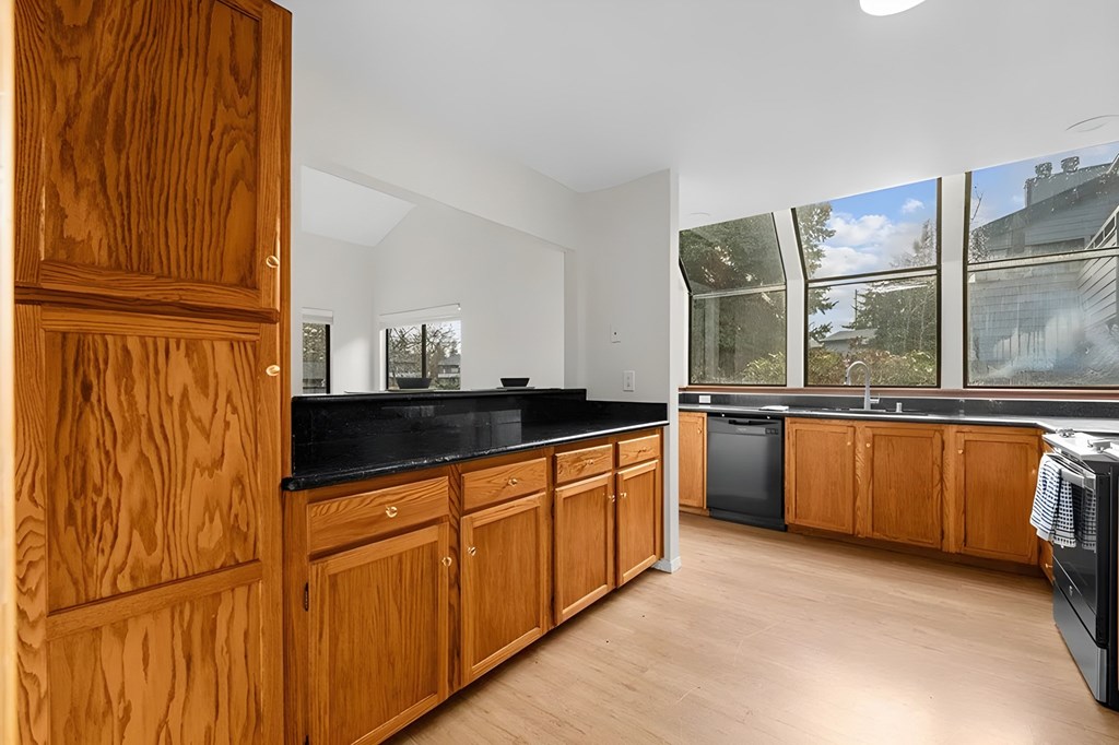 A kitchen with wooden cabinets and black countertops.