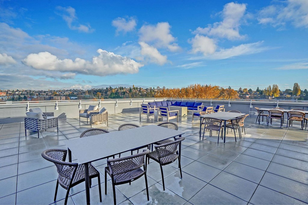 A patio with tables and chairs overlooking a cityscape.