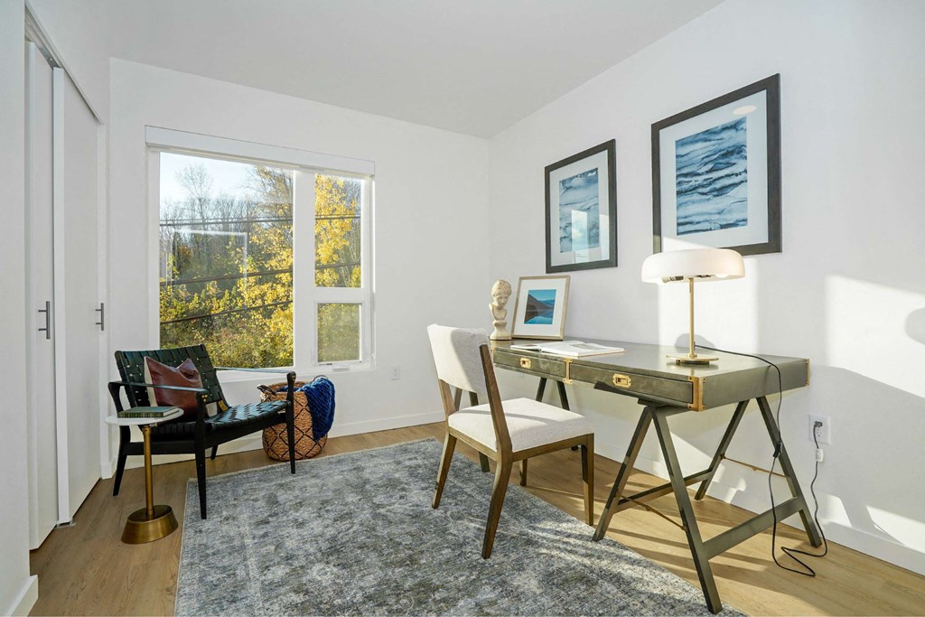 A room with a desk and chair in front of a window.