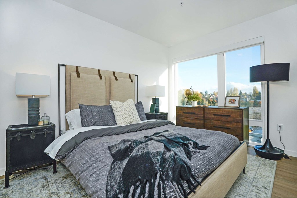 A bedroom with a large bed and a view of trees outside the window.