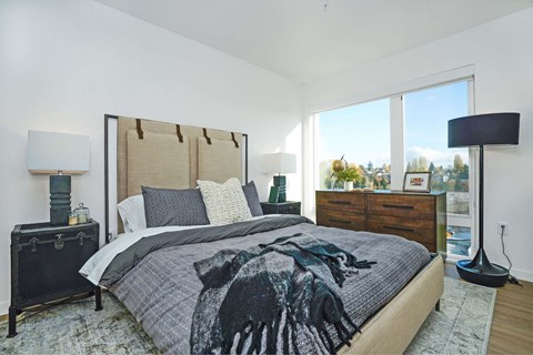 A bedroom with a large bed and a view of trees outside the window.