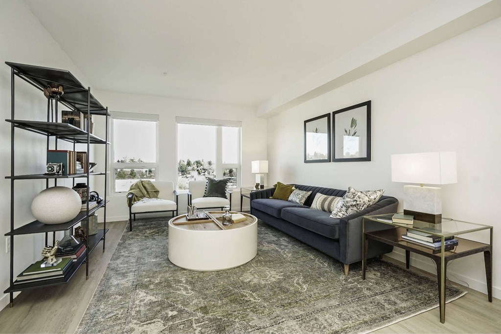 A modern living room with a dark blue sofa, a round coffee table, and a glass coffee table.