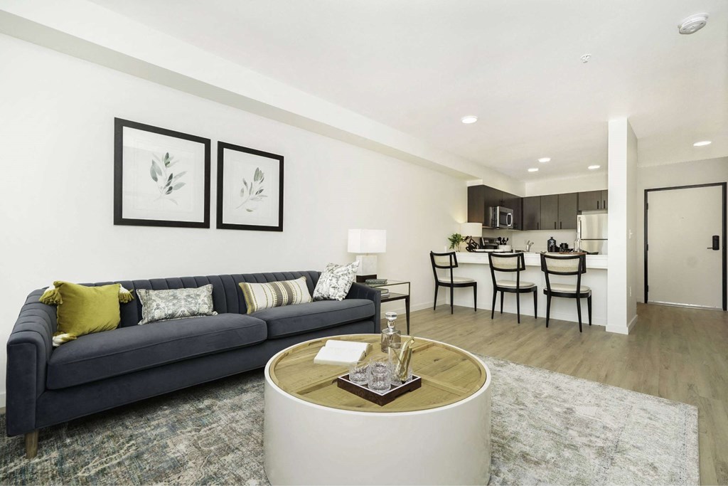 A living room with a grey couch, a coffee table, and a dining table with chairs.