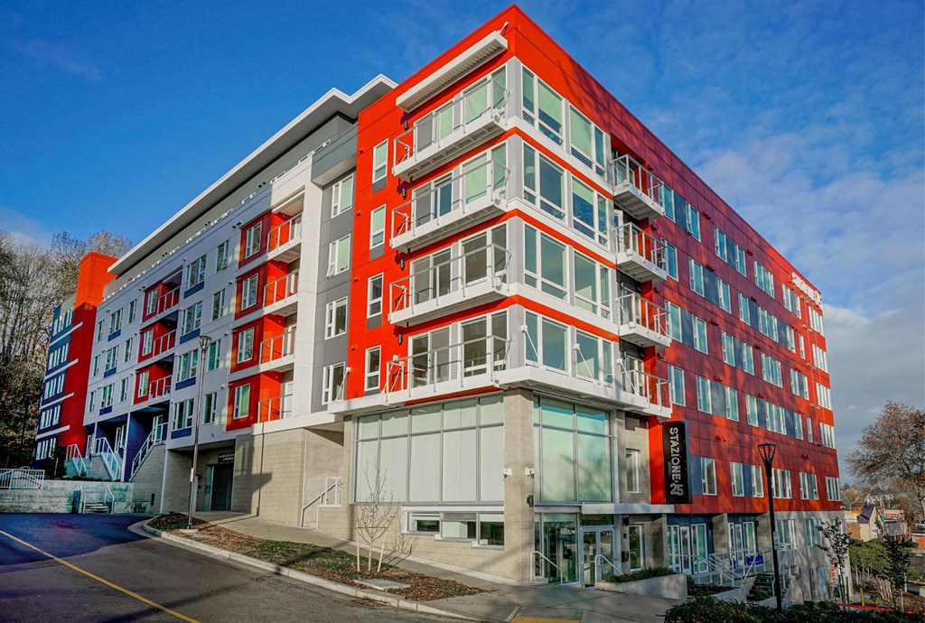 A modern multi-story building with red and white balconies.