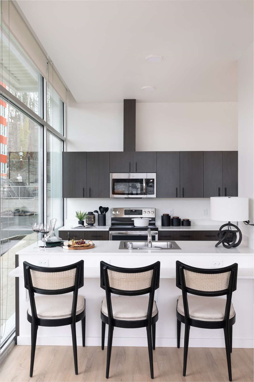 A modern kitchen with a white countertop and black chairs.