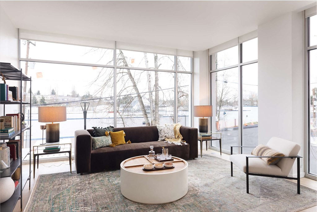 A living room with a brown couch, a white coffee table, and a large window.