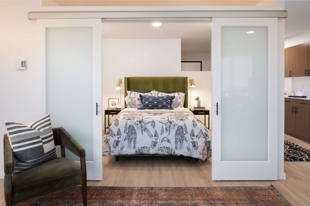 A bedroom with a bed, chair, and a rug.