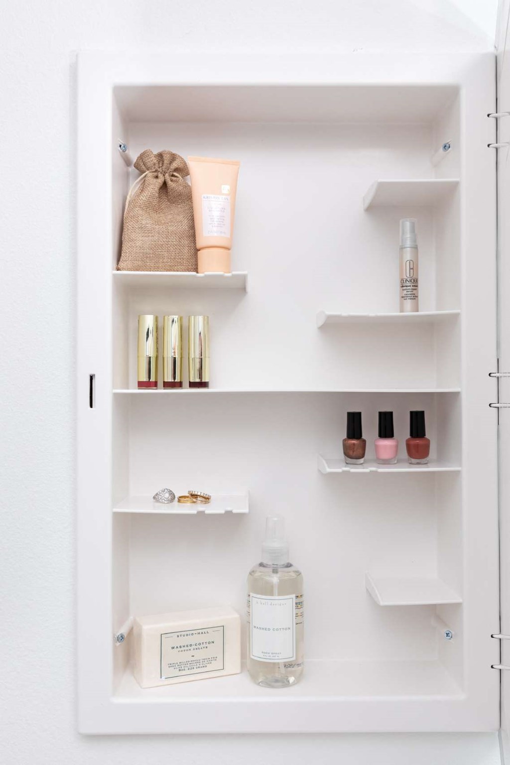 A white cabinet with various skincare products on shelves.