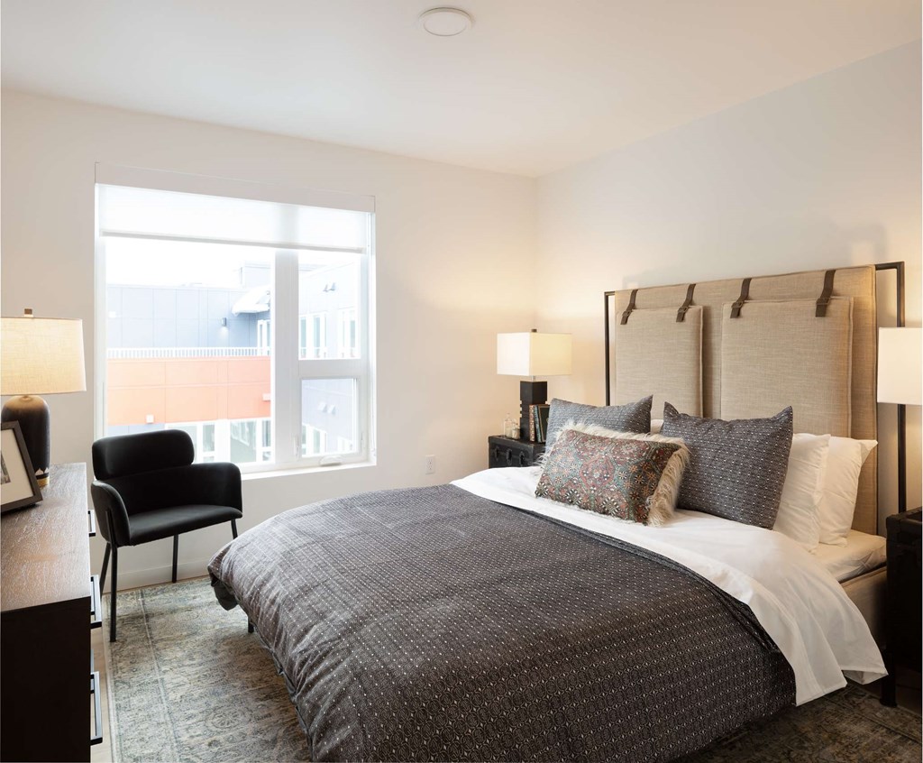 A bedroom with a large bed and a chair.