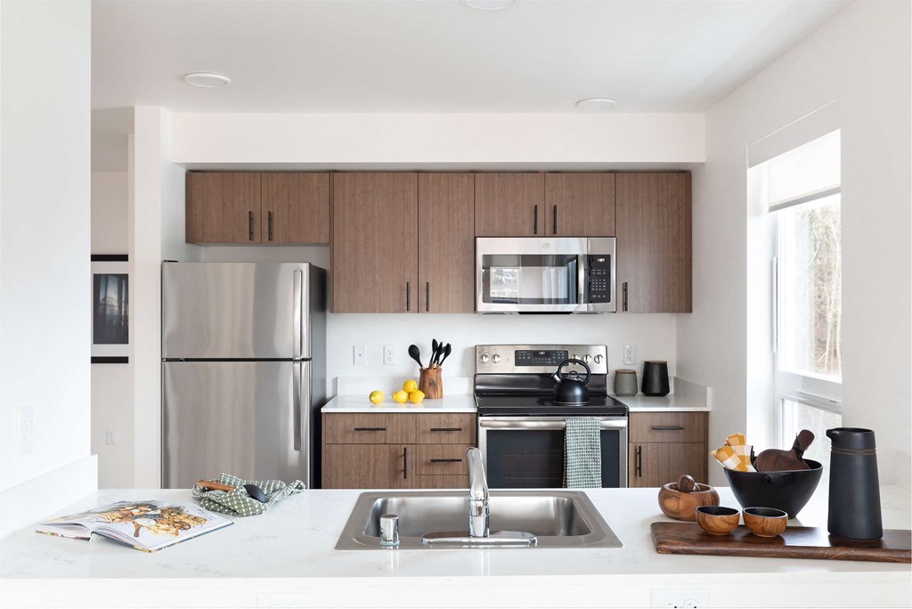 A modern kitchen with a stainless steel refrigerator, microwave, and oven.