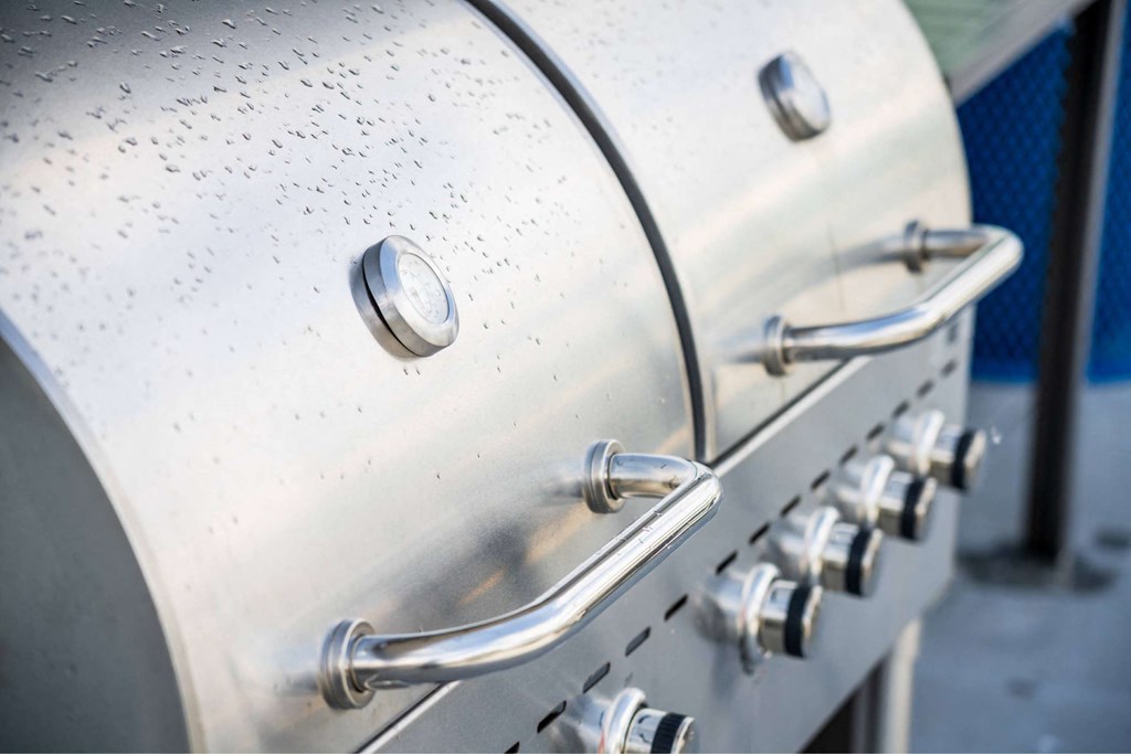 A close-up of a stainless steel grill with a handle and knobs.