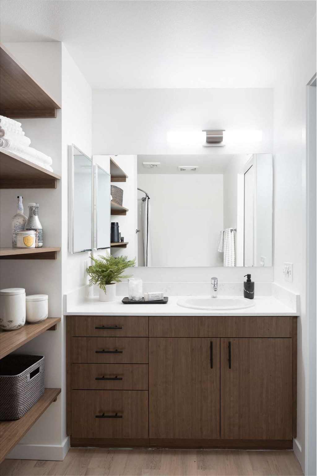A bathroom with a white sink and brown cabinets.