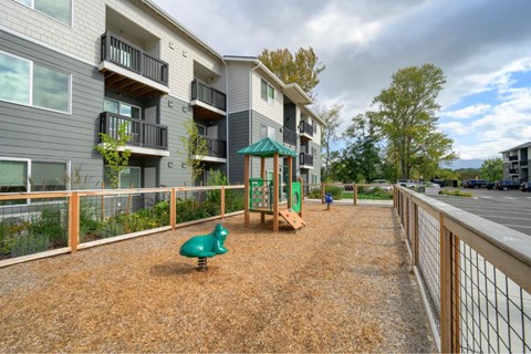 A playground area with a green slide and a green toy dinosaur.