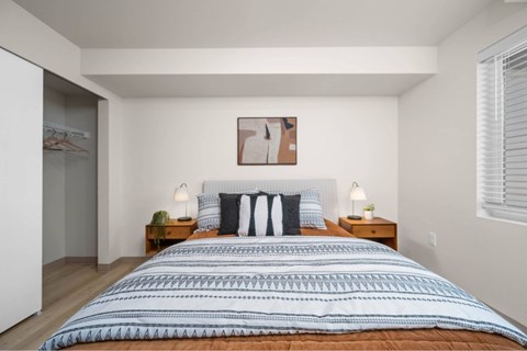 A bedroom with a large bed and two nightstands.