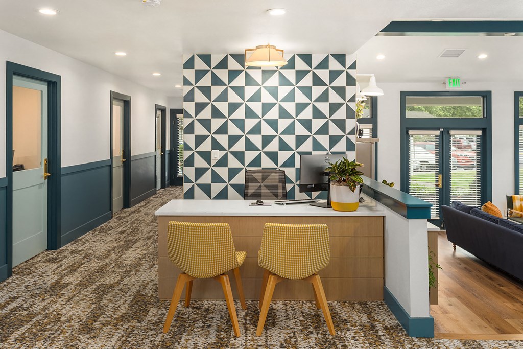a white kitchen with yellow chairs and a geometric wall