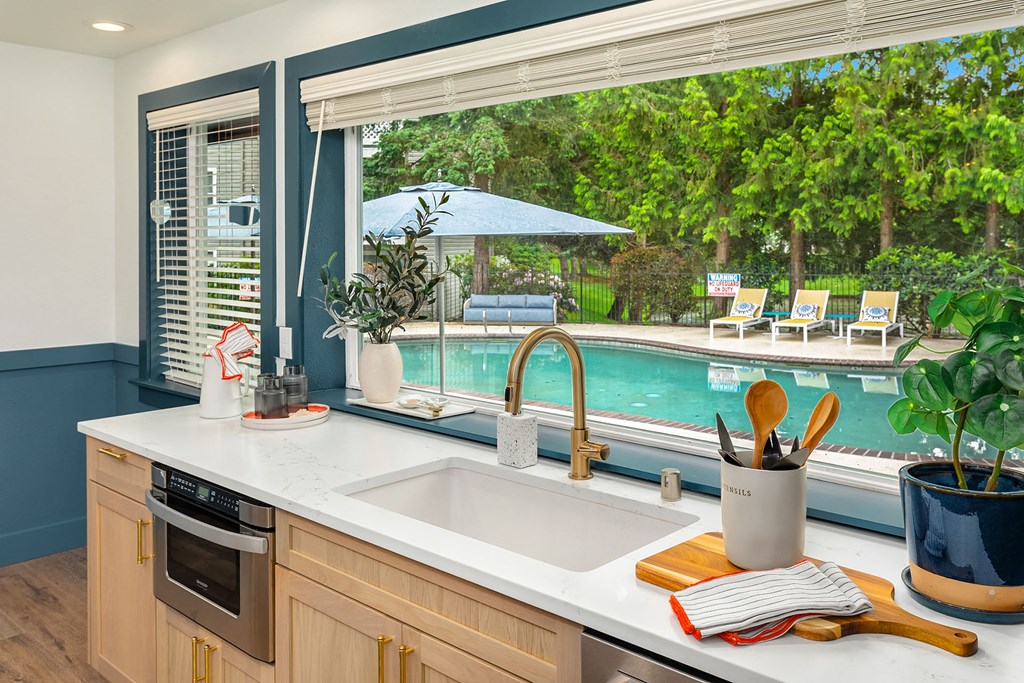 a kitchen with a sink and a window overlooking a swimming pool