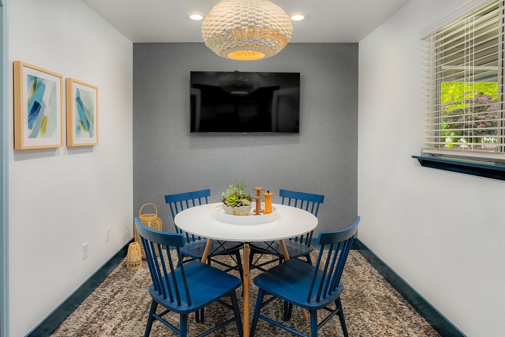 a dining area with a table and chairs and a tv on the wall