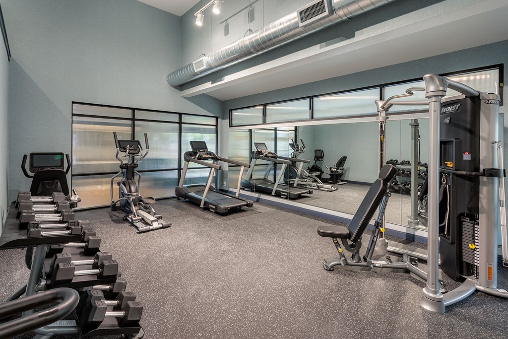 a gym with treadmills and other exercise equipment in a room with windows
