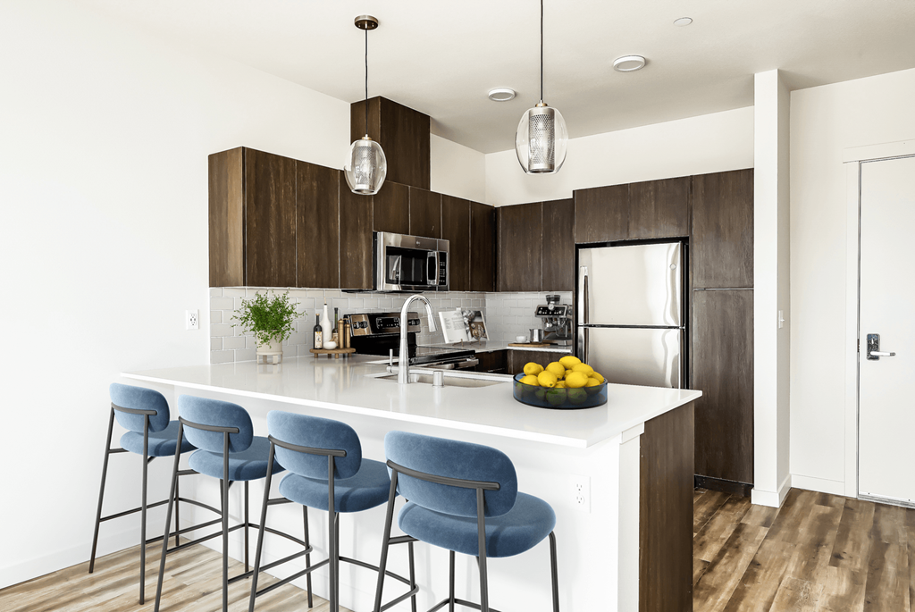 a kitchen with a large island with three blue bar stools in front of it