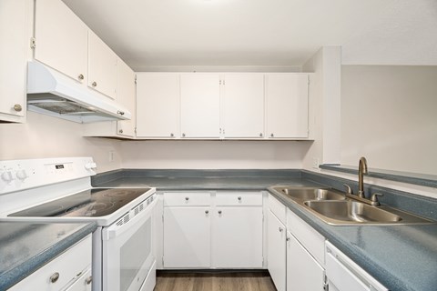 A kitchen with white cabinets and a stove top oven.