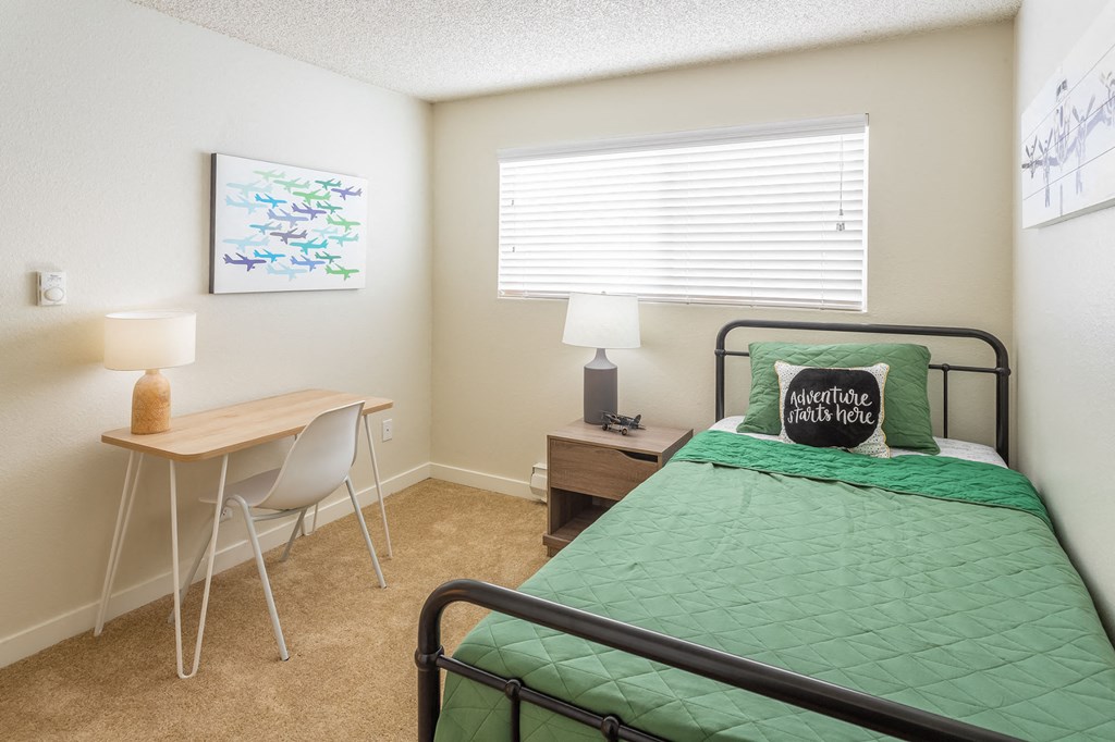 a bedroom with a bed and a desk and a window