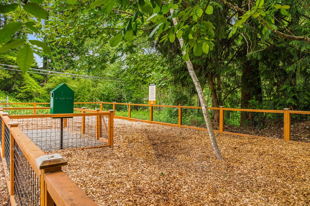 a fenced in area with a bird feeder and trees