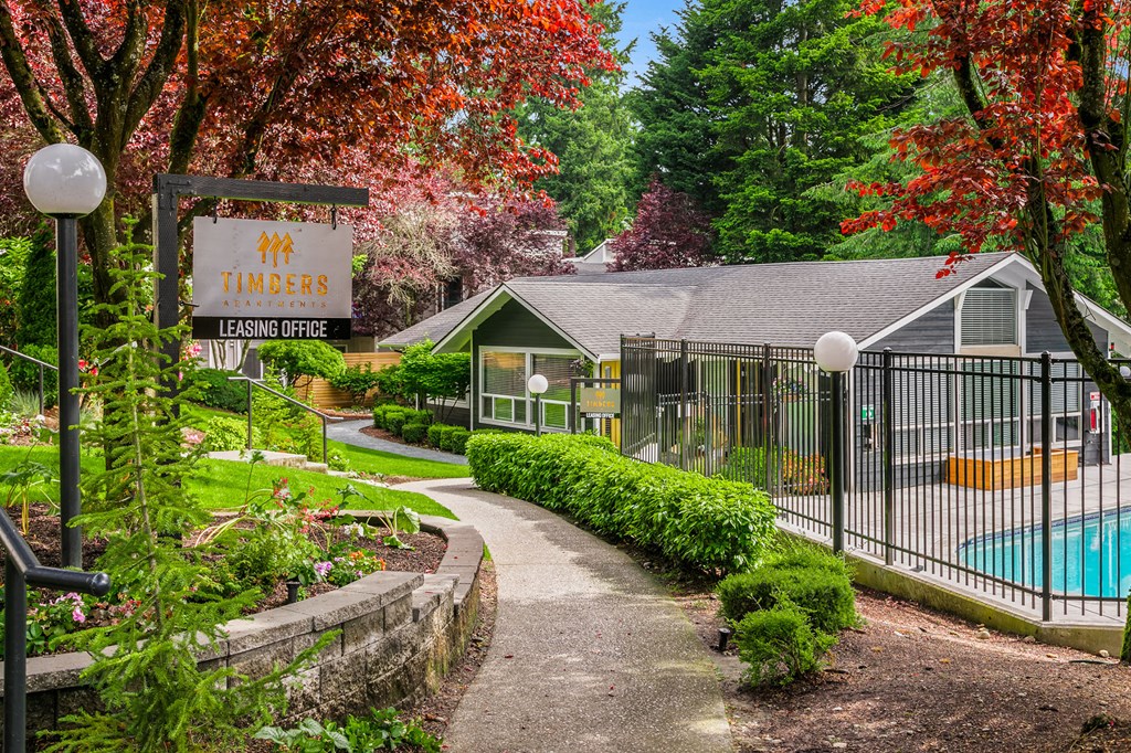 a yard with a pool and a house with a sign and a fence