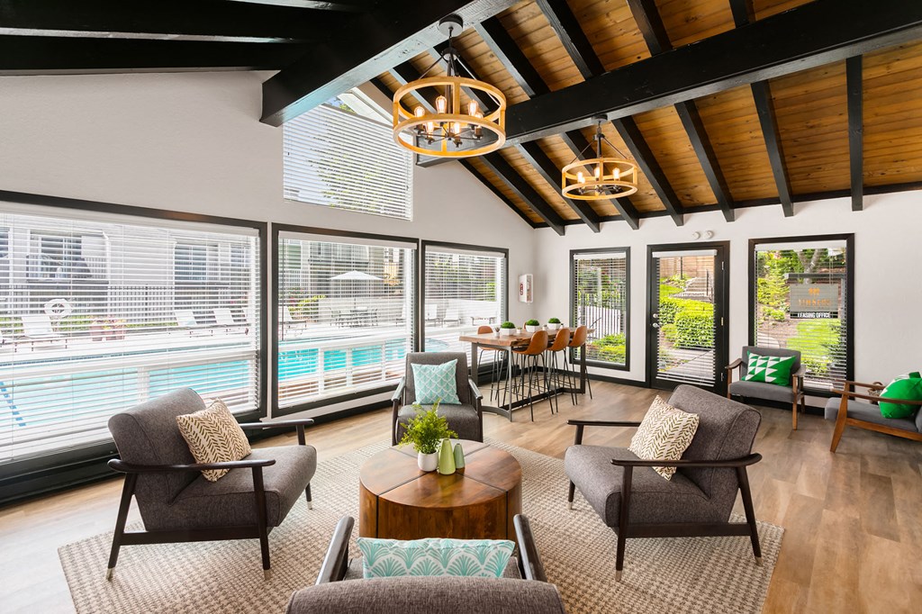 a living room with chairs and a table and large windows