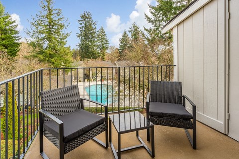 a balcony with two chairs and a pool