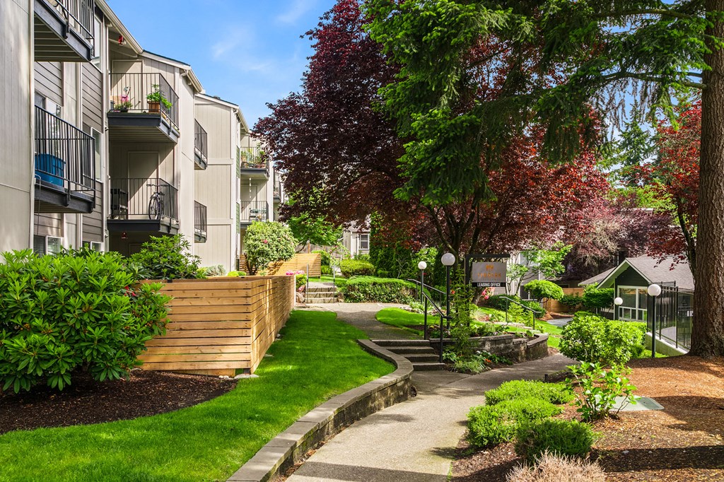 a walkway between two apartment buildings with grass and trees